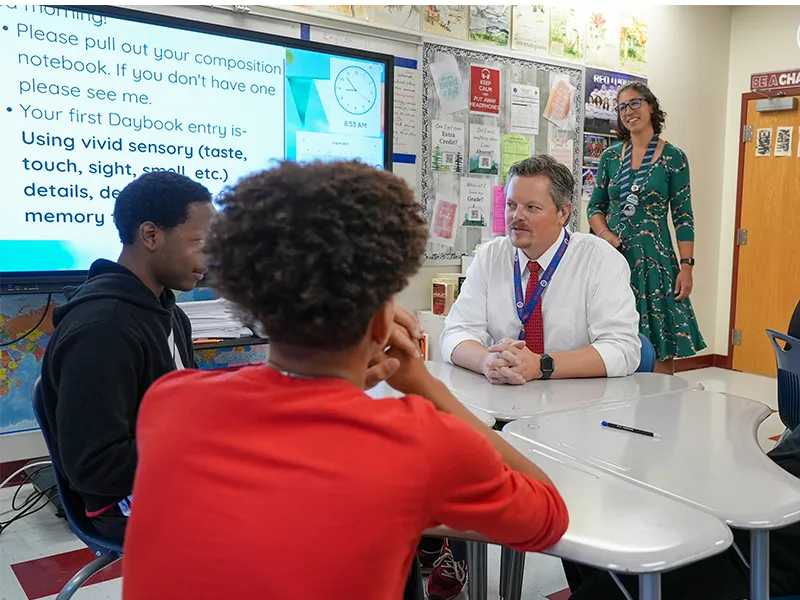 School administrator meeting with students at a table
