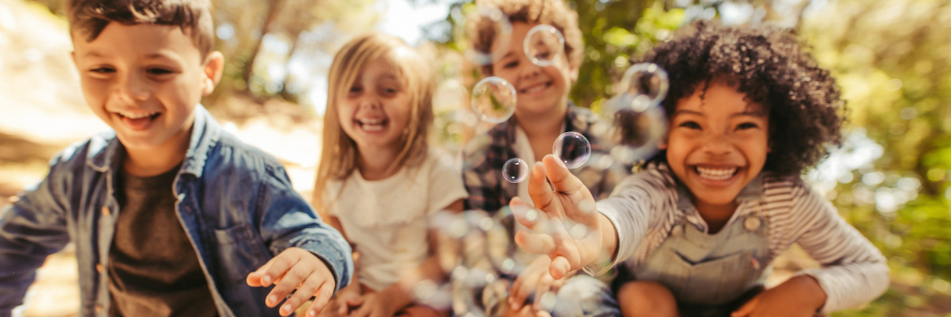 webpage banner showing 4 children smiling while playing with bubbles