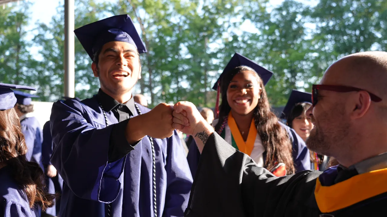 graduate from Patriot High School fist bumping teacher