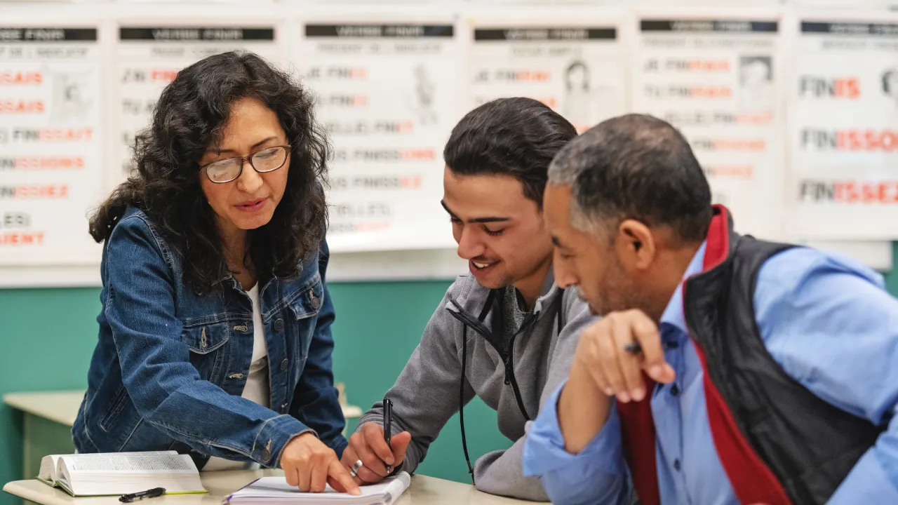 teacher helping two adult students