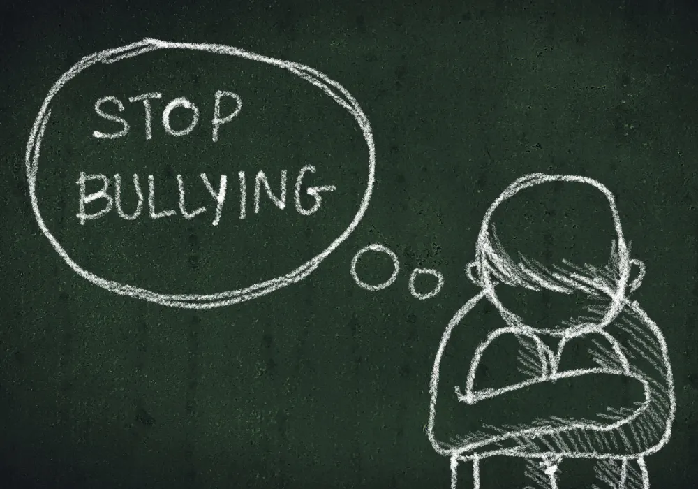 chalkboard drawing of a boy sitting with the words, stop bullying
