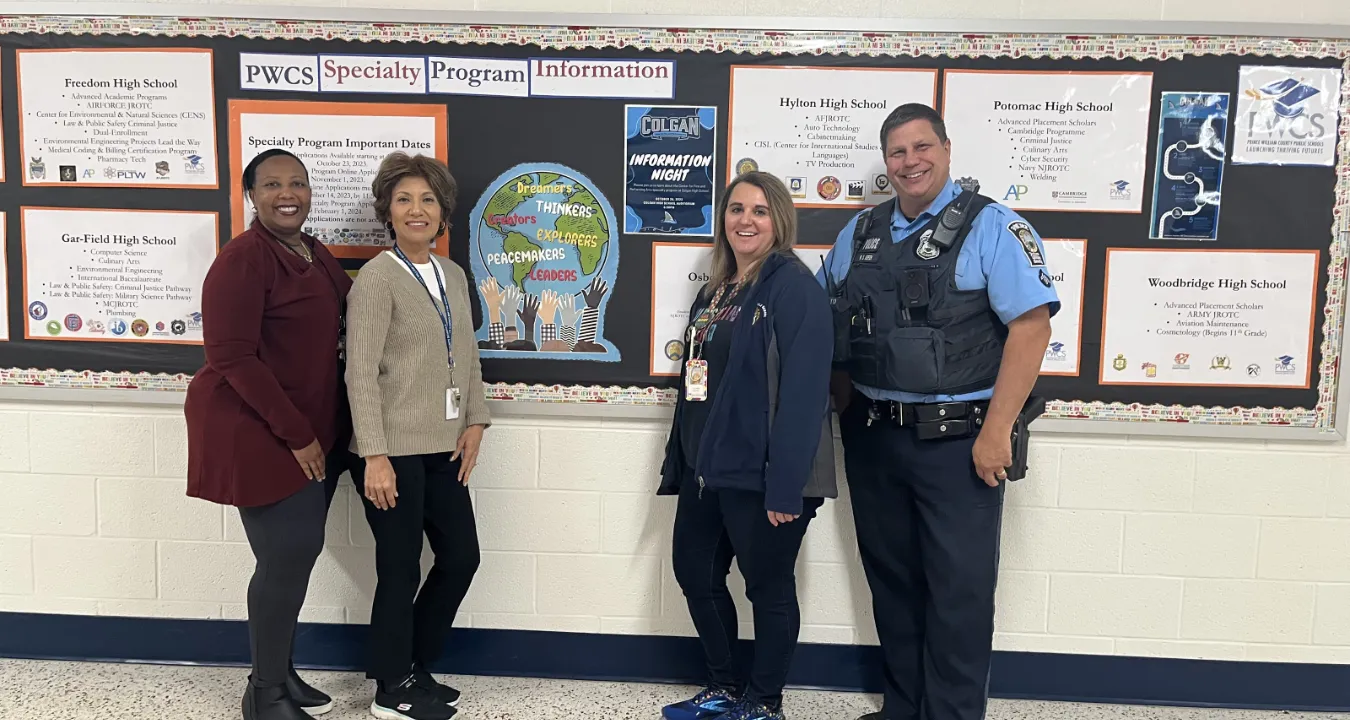 Prince William County police offiers standing in front of a bulletin board with PWCS staff at Beville Middle School