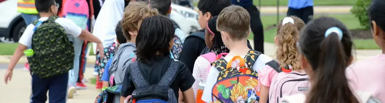 Elementary school students walking from their bus to enter their school