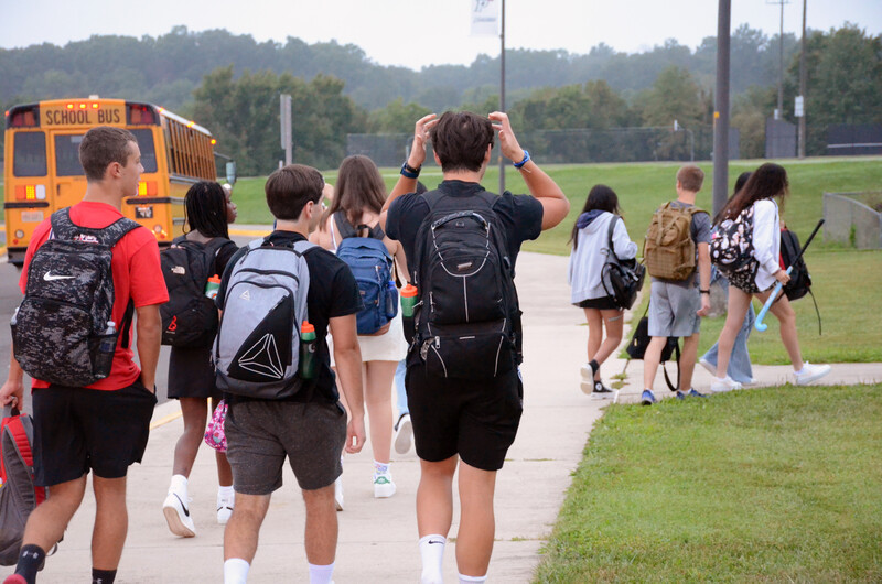 Students wearing backpacks walking together in groups 