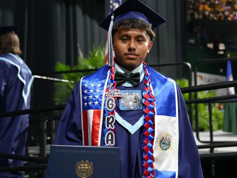 High school student posing for a photo after receiving their diploma