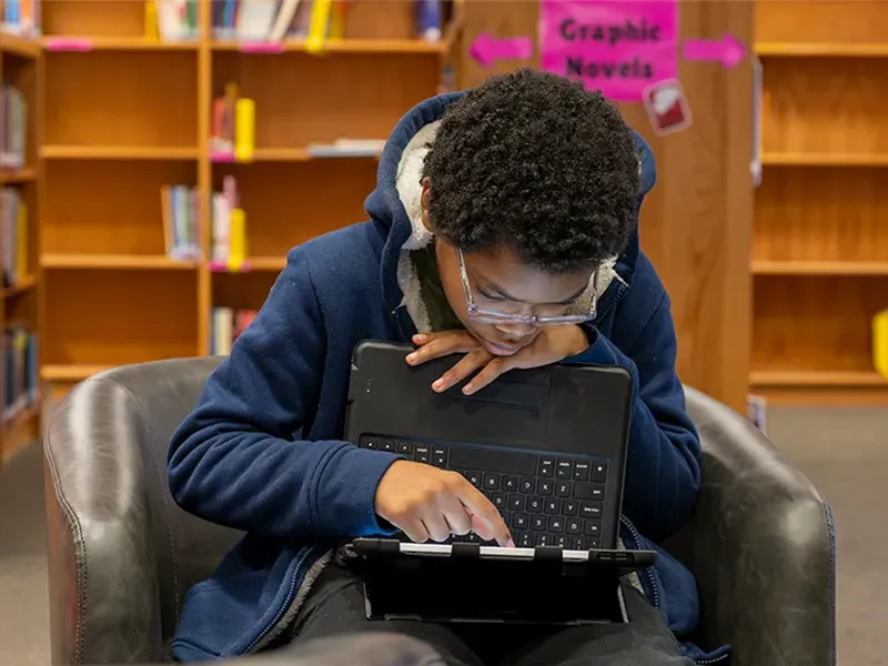 Middle school student seated while working on their iPad