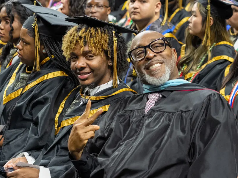 Freedom High school teacher poses for a photo while seated with student at the graduation ceremony