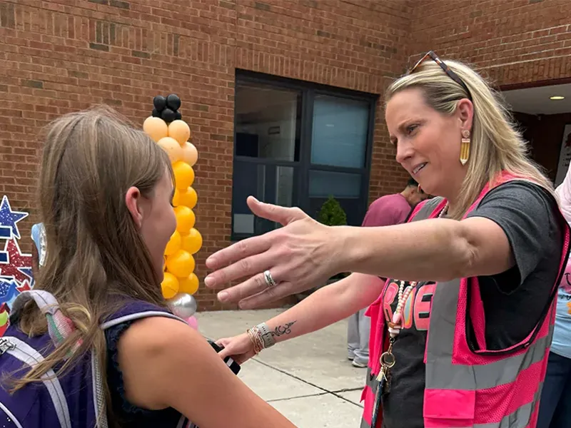 Staff member greeting a student with a hug on the first day of school