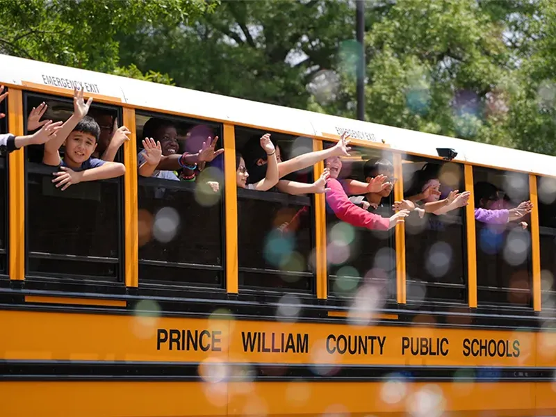 Students waving from bus windows on the last day of school