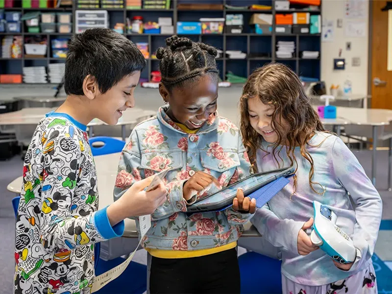 Three elementary school students holding and looking at an iPad