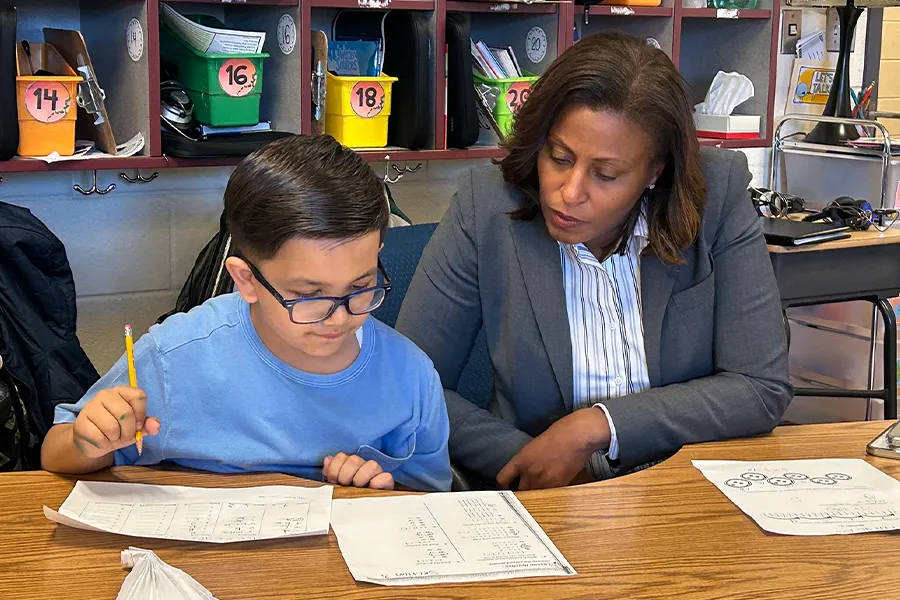 Superintendent Dr. McDade sitting with a boy in an elementary school classroom