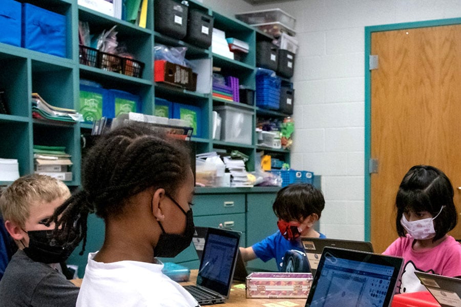 A group of young students in a classroom working at computers