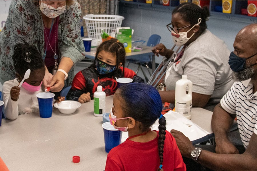 Parents and a teacher in a classroom with students