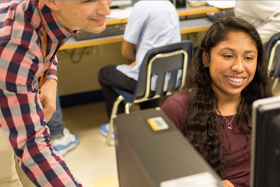 A person helping a student in a computer lab