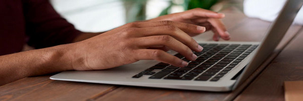 adult typing on laptop