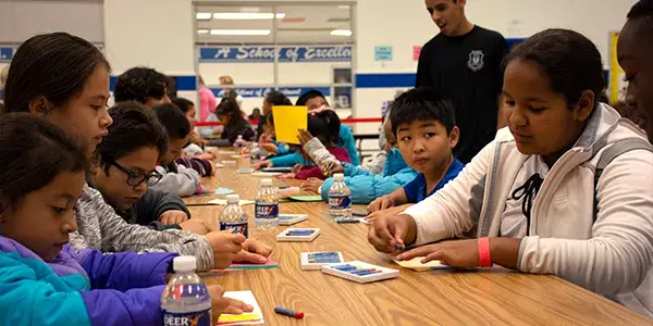 Families sitting at a school cafeteria table during a Parent Camp event