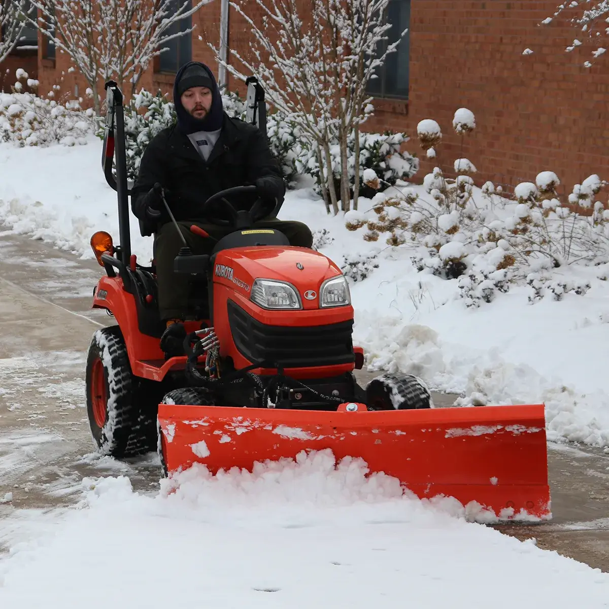 PWCS facilities staff member plowing snow with a lawn tractor at Henderson Elementary School