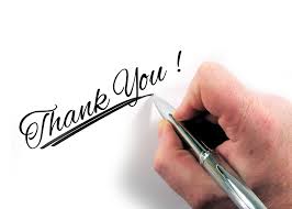A hand holding a pen with the words "Thank You" on a blank piece of paper