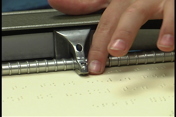 A person's hand reading Braille