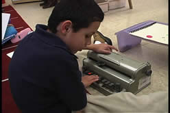 A student using a Perkins Braille Writer.