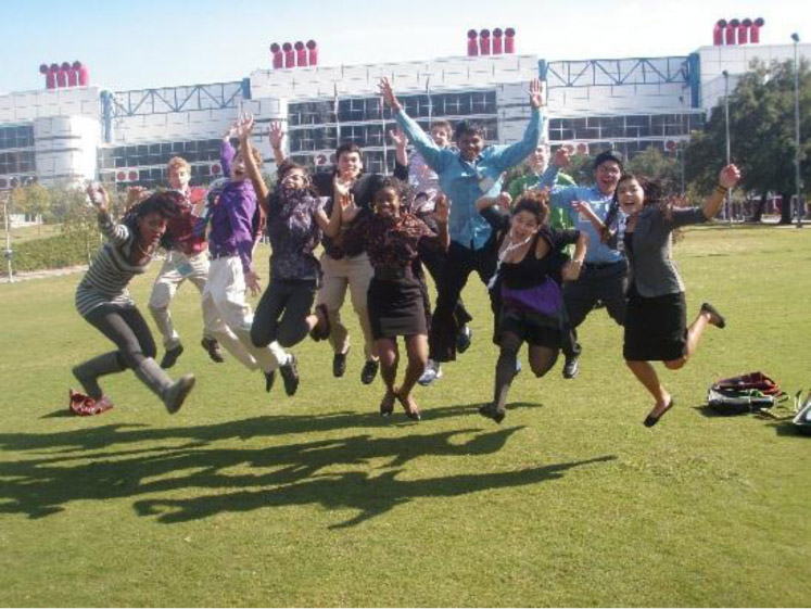 Group of students jumping in the air in front of a stadium
