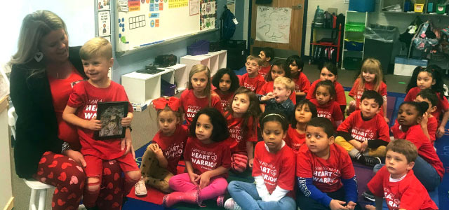 Cameron Barb sitting on his mom's lap with his classmates sitting on the carpet next to them.