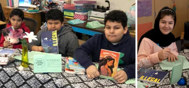 A group of students sitting at a table that is covered with a tablecloth showing off the books they selected