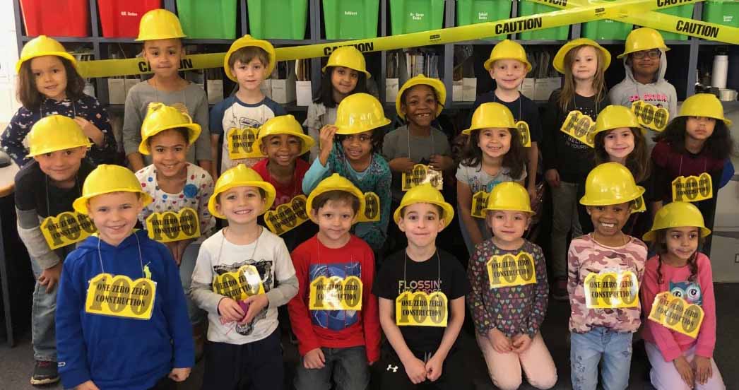 group of students wearing construction hats and 100 pictures around their necks