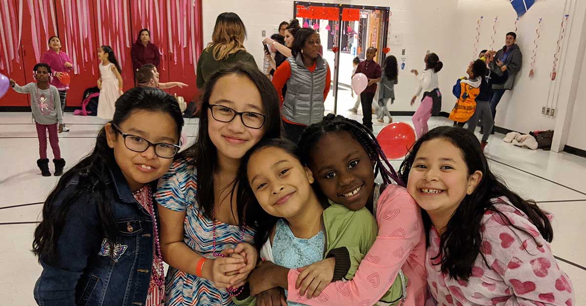 group of smiling girls with dancing happening in the background