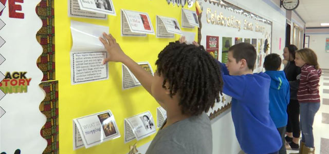 Students read information posted on a bulletin board for Black History Month