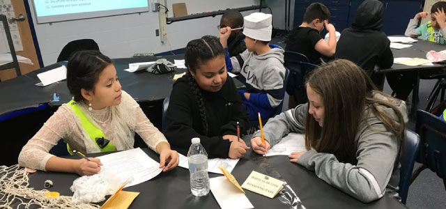 A group of three female students working together around a table 