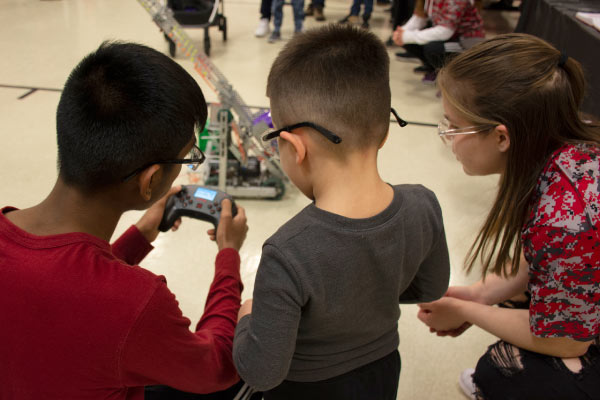 Three students working together on driving a robot