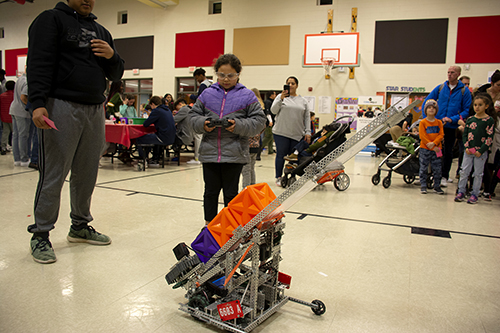 A female student and an adult working together to control a robot