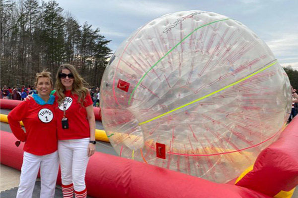 Two teachers who participated in the Westridge ES human hamster race standing next to the hamster ball outside