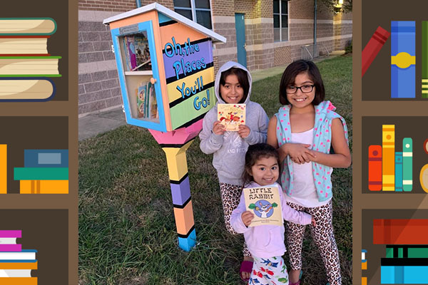 Three MWES students standing next to the Little Free Library