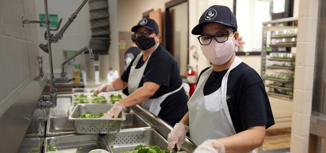 Two female cafeteria workers in a kitchen