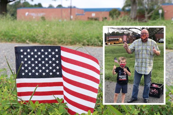 American flag sticking out of the grass in front of school. Insert picture of a young boy and older man holding the american flag.