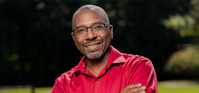 Photo of Fitzgerld Elementary School Music teacher Dr. Patrick Ware in an orange shirt with arms crossed