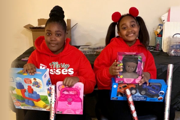 Natalya and Jalynn Barnwell sitting side-by-side, each holding two misc toys.