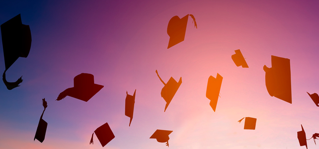 Graduation caps tossed in the air against a sunset