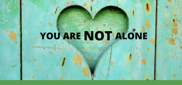 soft green wood-look background with a drawn heart in the center and the words "your are not alone" in the foreground