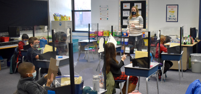 Teacher in front of her classroom speaking to students.