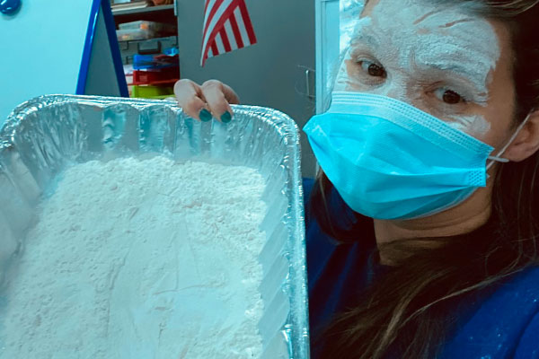 Teacher posing with a pan of flour