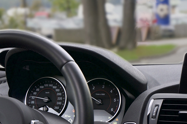 View of the dashboard and steering wheel of a car taken from back seat