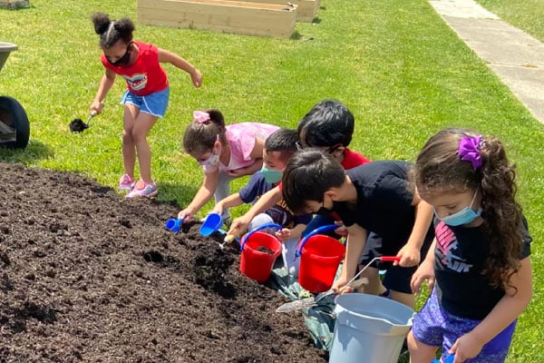 Elementary school students digging in a garden