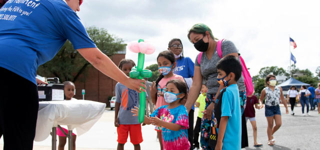 Student receiving balloon animal at community event