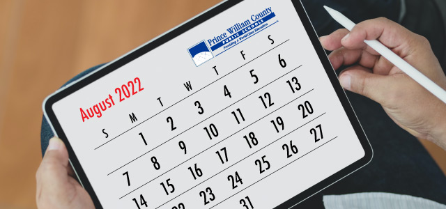 photo image of a tablet screen displaying a August 2022 month calendar and a person's hands holding the tablet and a stylus on their lap, to the left and around the image is a background that looks like wood flooring