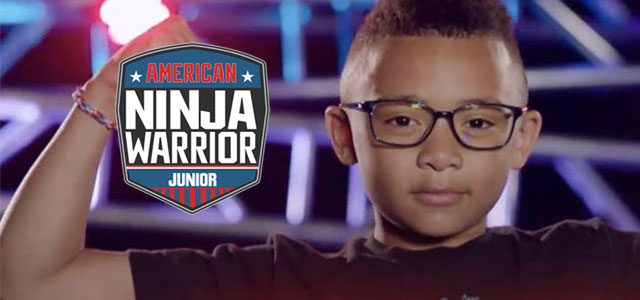 Large logo symbol of the TV show American Ninja Warrior Junior to the left of headshot of a determined looking young boy wearing glasses and with a spike-mohawk haircut