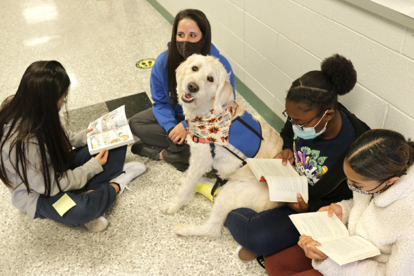 Bull Run Middle School students sitting on the floor and reading next to a therapy dog