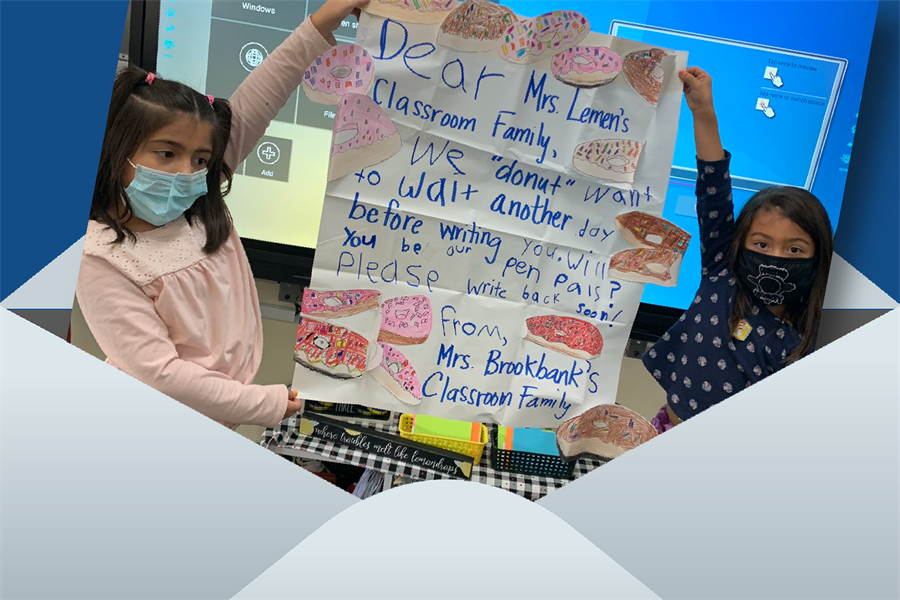 Two elementary school students holding up a poster written by Occoquan Elementary School students to Loch Lomond Elementary School students